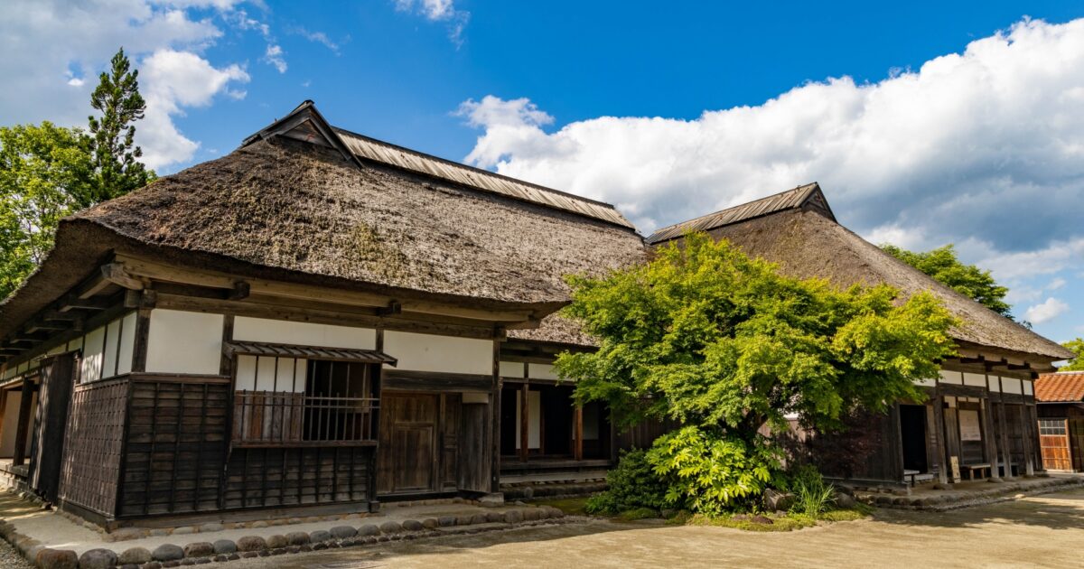 茅葺き屋根の古民家と青空