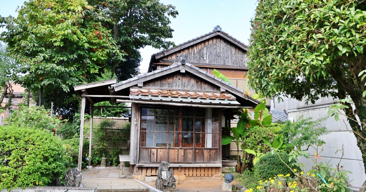 小さな木造の古民家と庭木
